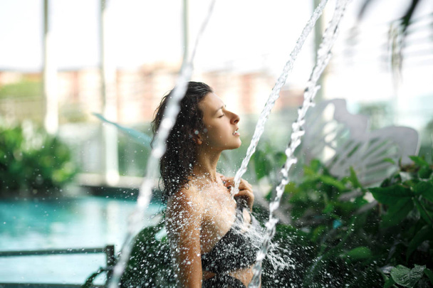 Sexy slim female in swimsuit takes shower in swimming pool betwe - Фото, зображення