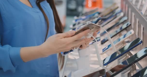 Fechar-se de mulheres mão escolher para comprar um novo telefone inteligente perto de uma vitrine em uma loja de eletrônicos
 - Filmagem, Vídeo