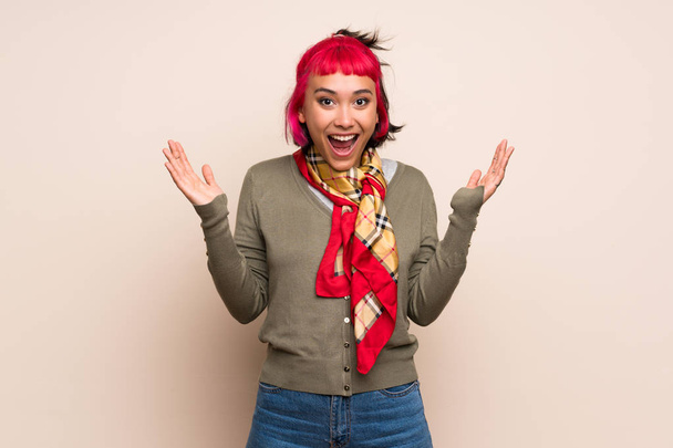 Giovane donna con capelli rosa sopra la parete gialla con espressione facciale scioccata
 - Foto, immagini
