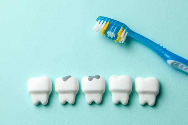 Gezonde witte tanden en tand met cariës op groene munt achtergrond en tandenborstel. - Foto, afbeelding