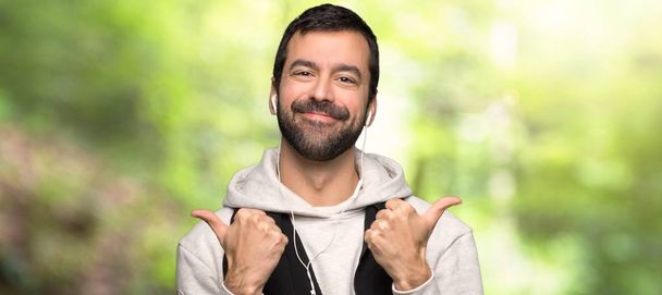 Sport man giving a thumbs up gesture with both hands and smiling in a park - Photo, Image