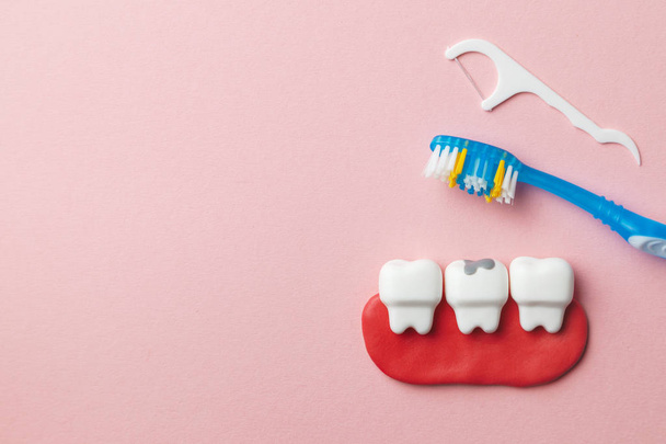 Egészséges fehér fogak és fogak a fogszuvasodás a rózsaszín háttér és a fogkefe és fogselyem. A szöveg másolása szóközzel. - Fotó, kép