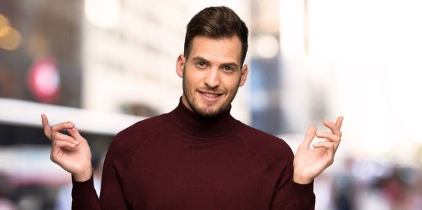 Man with turtleneck sweater having doubts while raising hands in the city - Foto, immagini