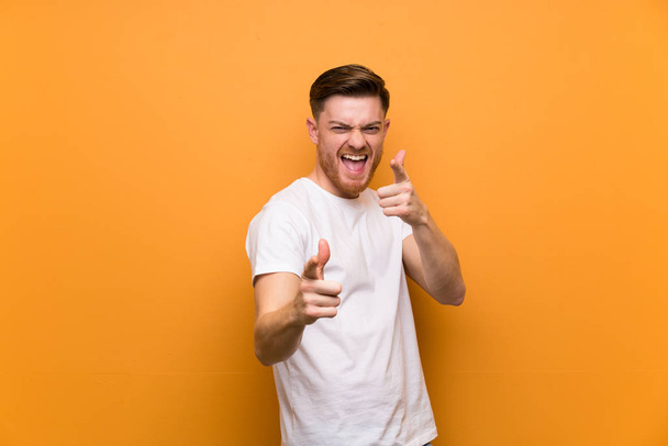 Redhead man over brown wall pointing to the front and smiling - Photo, Image
