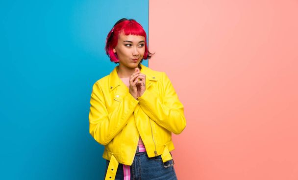 Young woman with yellow jacket scheming something - 写真・画像