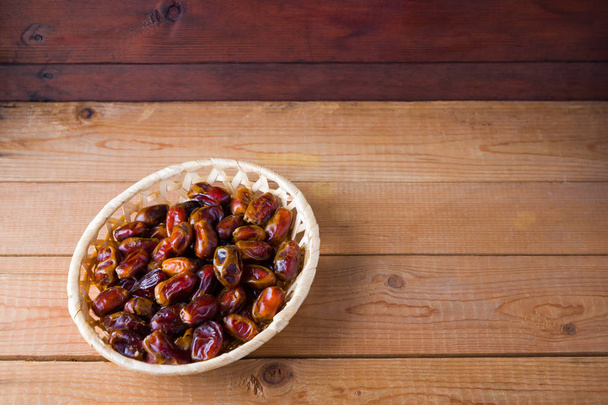 Dates on wooden background. Holy month of Ramadan, concept. Righteous Muslim lifestyle. Starvation. Dates in a wooden basket in the style of minimalism. Copy space - Zdjęcie, obraz