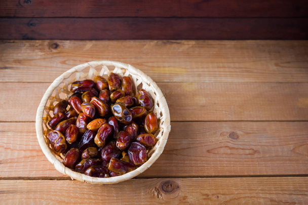 Dates on wooden background. Holy month of Ramadan, concept. Righteous Muslim lifestyle. Starvation. Dates in a wooden basket in the style of minimalism. Copy space - Foto, Bild