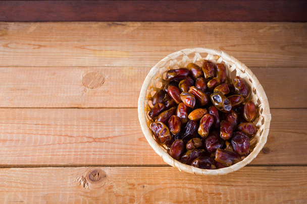 Dates on wooden background. Holy month of Ramadan, concept. Righteous Muslim lifestyle. Starvation. Dates in a wooden basket in the style of minimalism. Copy space - Valokuva, kuva