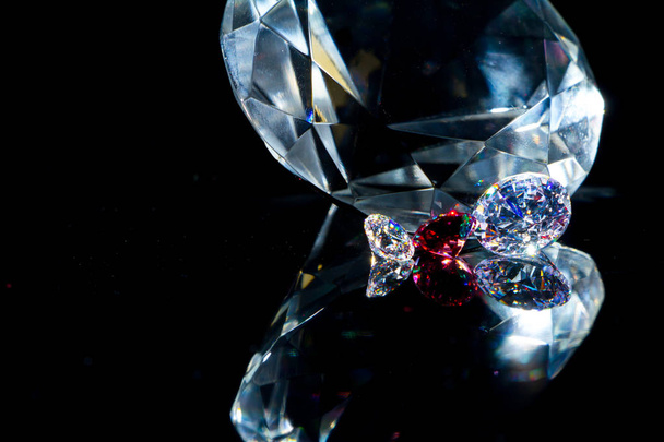 Obrovský diamant a několik elegantních krystalů na černém zrcadlovém povrchu, třpytičivý a jiskřící. - Fotografie, Obrázek