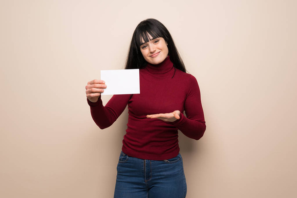 Young woman with red turtleneck holding an empty placard for insert a concept - Φωτογραφία, εικόνα
