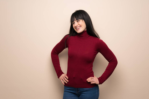 Young woman with red turtleneck posing with arms at hip and laughing - Foto, immagini