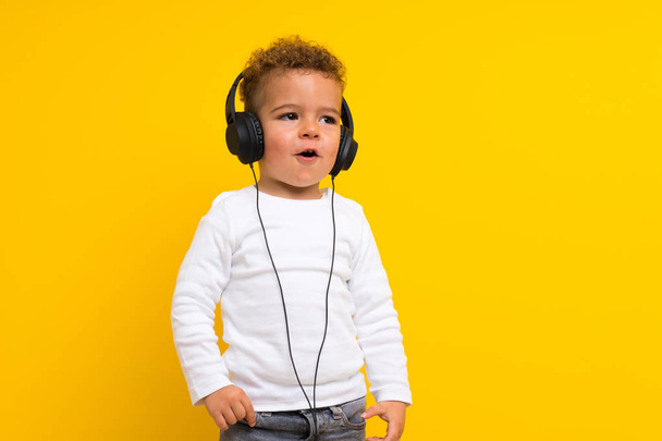kid over isolated purple background listening music - Фото, изображение
