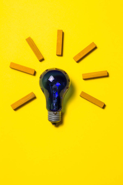 Blue light bulb on yellow background - Zdjęcie, obraz