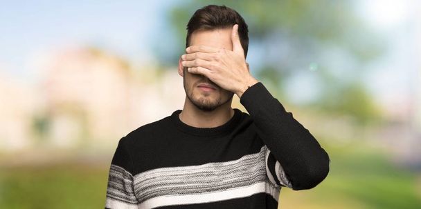Handsome man covering eyes by hands. Do not want to see something at outdoors - Photo, Image