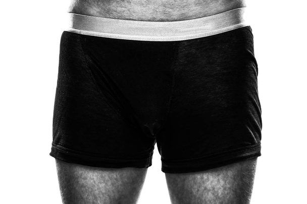 Κοντινό πλάνο ενός αρσενικού τριχωτού άντρα που στέκεται στο μαύρο μπόξερ σορτς απομονώνεται σε λευκό φόντο-έννοια του ανίκανο φίλο, σύζυγο ή εραστή, σεξουαλική αγάπη και την εμπιστοσύνη του φύλου στο υπνοδωμάτιο - Φωτογραφία, εικόνα