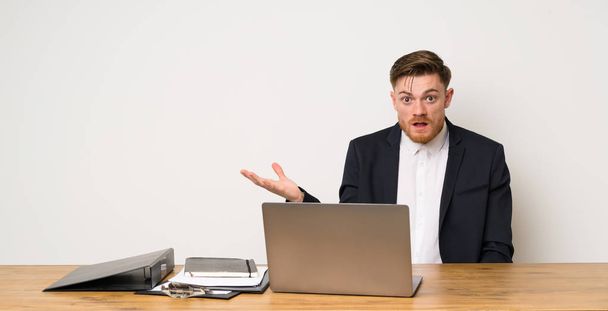 Businessman in a office making doubts gesture - Foto, afbeelding