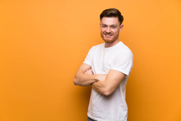 Redhead man over brown wall with arms crossed and looking forward - Photo, image