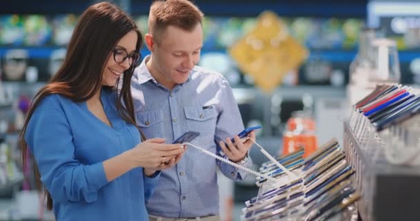 Ember gazdaság okos telefon és rámutatva más telefon, amely a nő kezében. Belső Tech áruház. - Felvétel, videó