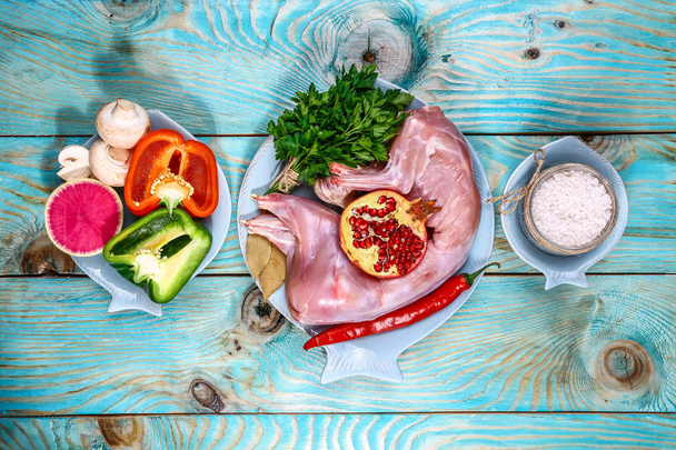 Raw rabbit meat ready to be cooked. on a wooden Board with ingredients on a wooden background - top view. Concept of Dietary Nutrition - Photo, Image