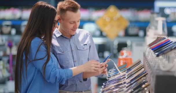 La pareja elige un teléfono móvil en una tienda electrónica. Escaparate con smartphones
 - Imágenes, Vídeo