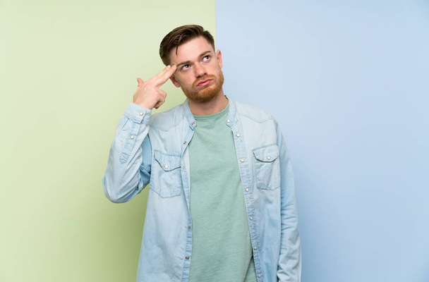 Redhead man over colorful background with problems making suicide gesture - Valokuva, kuva