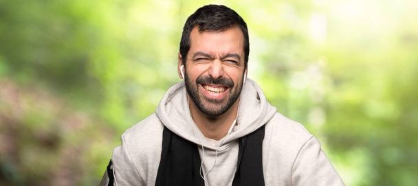 Sportovní muž, který se hodně usmívá při oblékování hrudníku do parku - Fotografie, Obrázek