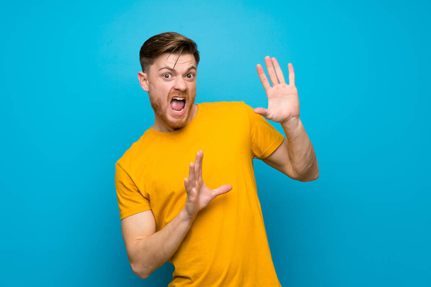 Redhead man over blue wall nervous and scared - Foto, Bild