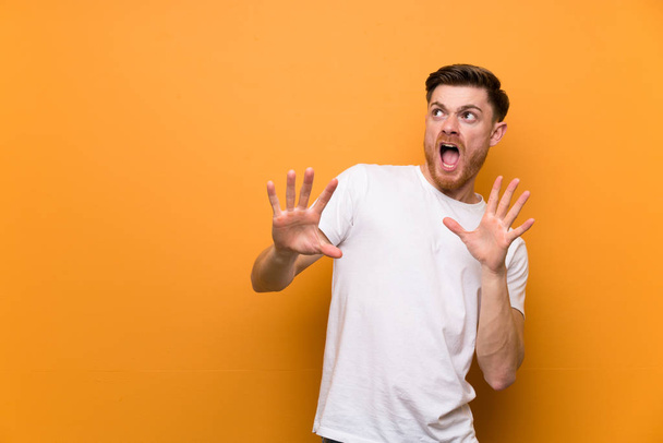 Redhead man over brown wall nervous and scared - 写真・画像