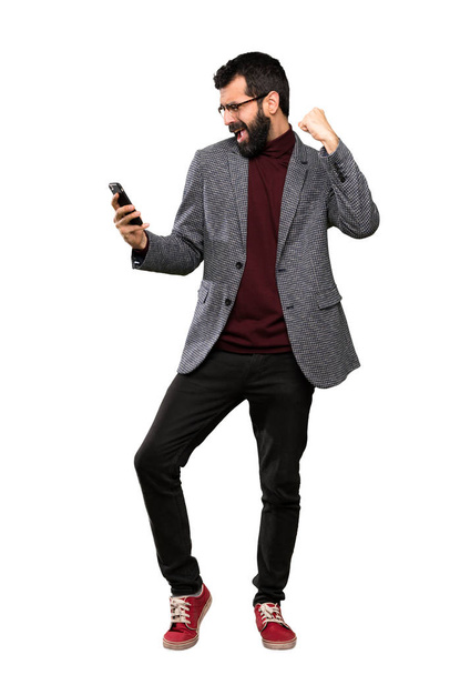 Handsome man with glasses with phone in victory position over isolated white background - Foto, Imagen