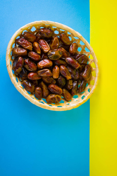 Dried dates on a yellow blue background. Holy month of Ramadan, concept. Righteous Muslim lifestyle. Starvation. Dates in a wooden basket in the style of minimalism - Foto, Imagem