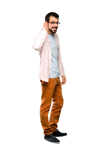 Full-length shot of Handsome man with beard listening to something by putting hand on the ear over isolated white background - Photo, Image