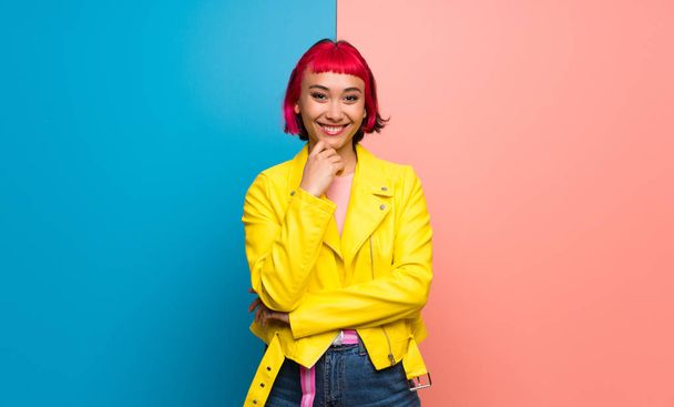 Young woman with yellow jacket smiling and looking to the front with confident face - Foto, afbeelding
