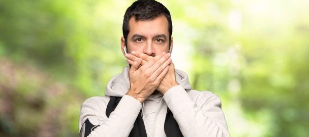 Hombre de deporte cubriendo la boca con las manos por decir algo inapropiado en un parque
 - Foto, Imagen