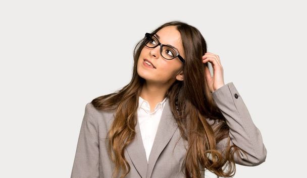 Donna d'affari pensando un'idea mentre gratta la testa su sfondo grigio isolato
 - Foto, immagini