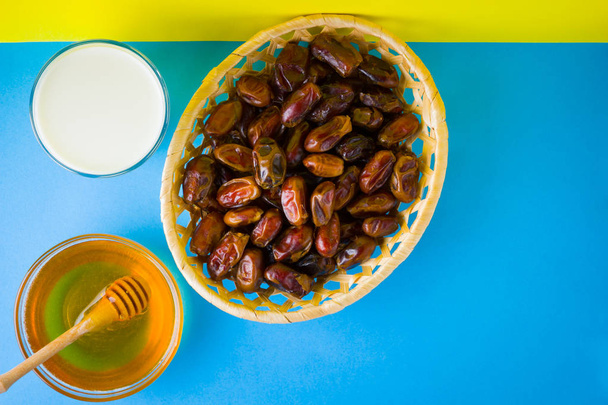 Dried dates, milk and honey on a yellow blue background. Holy month of Ramadan, concept. Righteous Muslim lifestyle. Starvation. Dates in a wooden basket in the style of minimalism - Valokuva, kuva