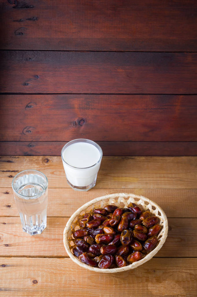 Dried dates and milk on wooden background. Holy month of Ramadan, concept. Righteous Muslim lifestyle. Starvation. Dates in a wooden basket in the style of minimalism. Copy space - Zdjęcie, obraz