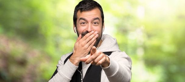 Спортивный человек указывает пальцем на кого-то и смеется в парке
 - Фото, изображение