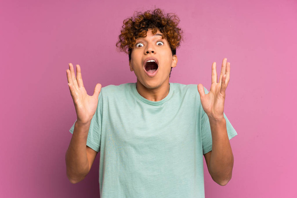 Молодий афроамериканець людини над ізольованою фіолетовою стіною з сюрпризом вираз обличчя - Фото, зображення
