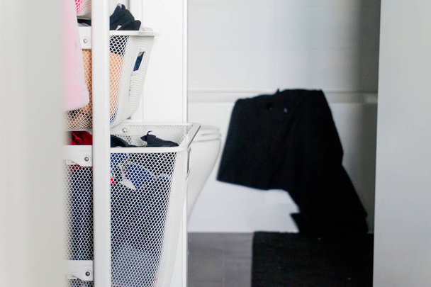 Vêtements dans le placard organisateurs de panier de tiroir, avec salle de bains en arrière-plan, et serviette noire suspendue sur la baignoire
. - Photo, image