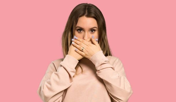 Teenager girl with pink sweater covering mouth with hands for saying something inappropriate over isolated pink background - Photo, Image