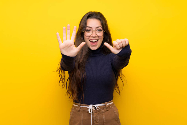 Teenager girl over isolated yellow wall counting six with fingers - Photo, Image