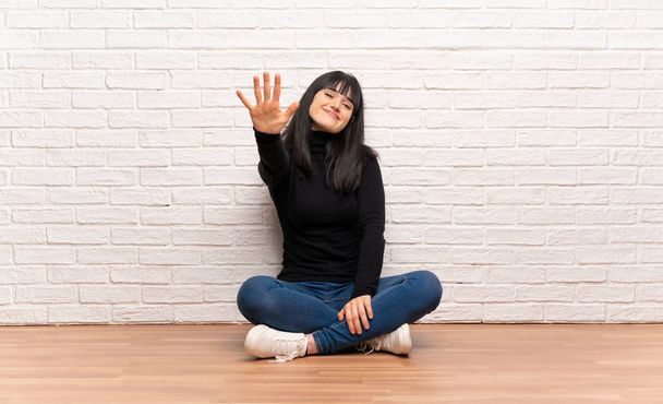 Γυναίκα που κάθεται στο πάτωμα μετρώντας πέντε με τα δάχτυλα - Φωτογραφία, εικόνα