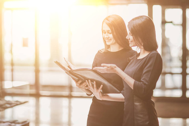 two business women read business documents standing in the office lobby. - Photo, image