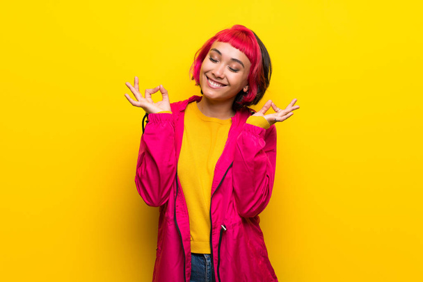 Young woman with pink hair over yellow wall in zen pose - Foto, Imagem