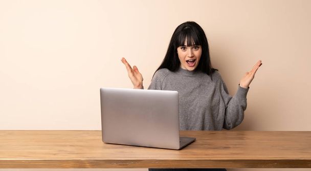 Young woman working with her laptop with shocked facial expression - Foto, Imagen