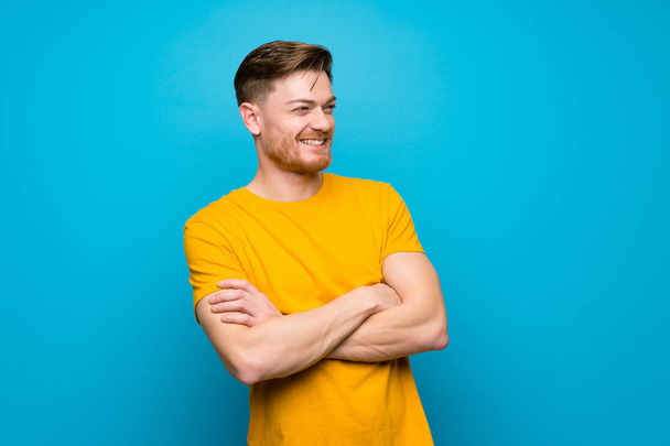 Redhead muž s modrou stěnou šťastný a usměvavý - Fotografie, Obrázek