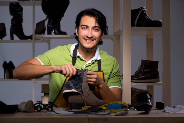 Jonge schoenmaker in workshop bij nacht  - Foto, afbeelding