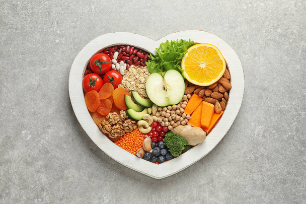 Heart shaped tray with healthy products on grey background, top view - Foto, imagen