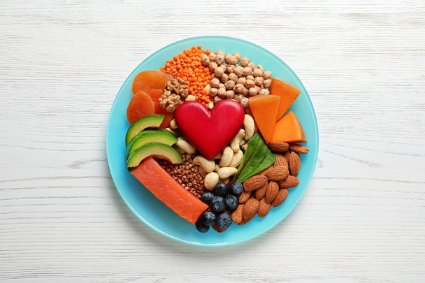 Plate with heart-healthy products on wooden background, top view - Fotó, kép