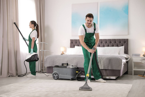 Team of janitors cleaning bedroom with professional equipment - Foto, Bild